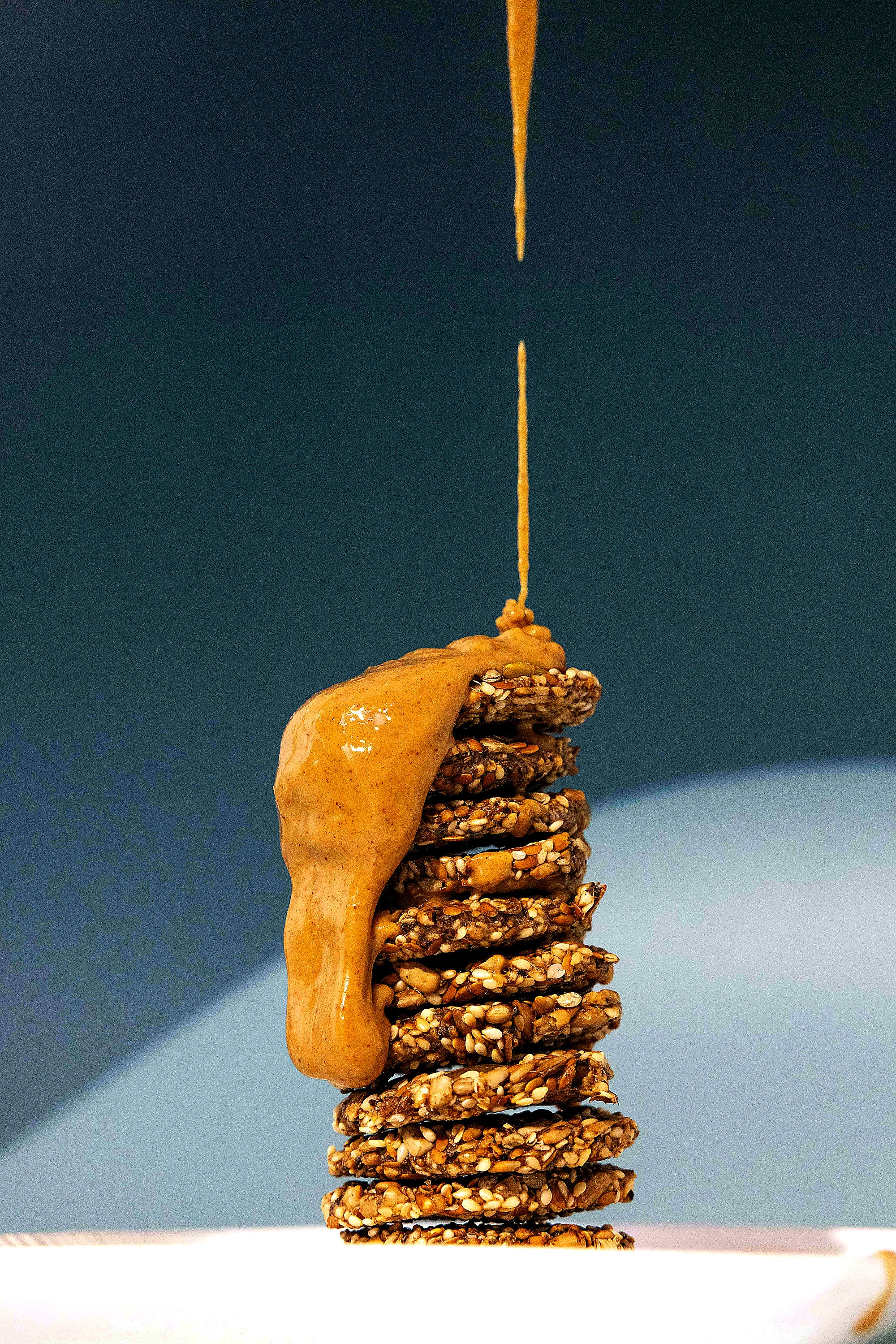 Stack of seed crackers with almond butter drizzled on top, showing texture